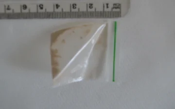 Petit sachet contenant des résidus d'héroïne brune, à côté d'une règle